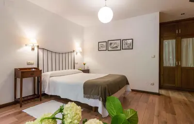a bedroom with a white bed and a wooden floor at Apartamentos Rurales Sierra in Palacio de Naviego