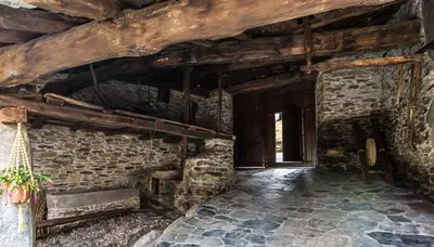 a room with a stone wall with a wooden ceiling at Apartamentos Rurales Sierra in Palacio de Naviego