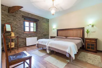 a bedroom with two beds and a stone wall at Apartamentos Rurales Sierra in Palacio de Naviego