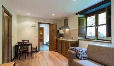 a living room with a couch and a table and a kitchen at Apartamentos Rurales Sierra in Palacio de Naviego