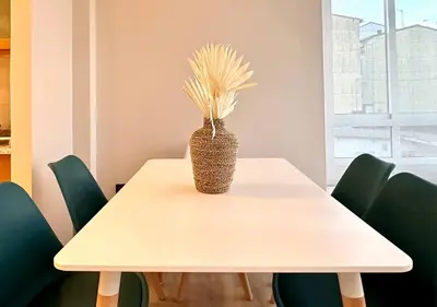 a white table with a vase on it with green chairs at Os Potes Flat in Ares