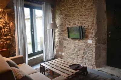a living room with a bench and a stone wall at Casa Peón de Pardaces in Santiago de Compostela