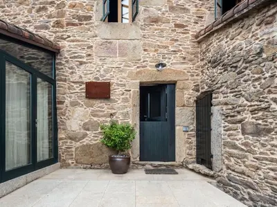 a stone building with a door and a potted plant at Casa Peón de Pardaces in Santiago de Compostela