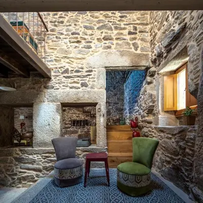 a living room with two chairs and a stone wall at Casa Peón de Pardaces in Santiago de Compostela
