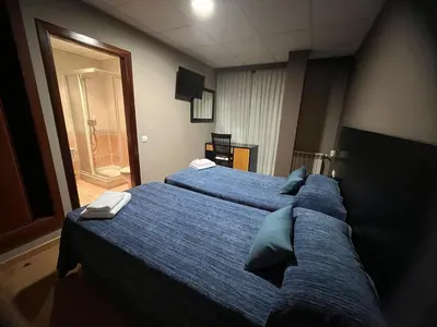 a hotel room with two beds with blue sheets at Pension Luscofusco in Puebla de Trives