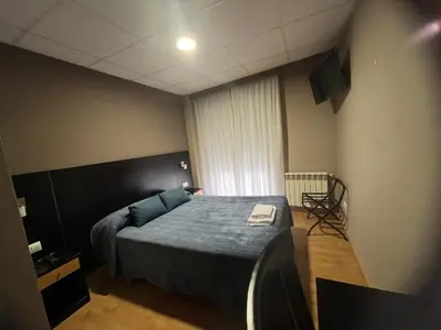 a bedroom with a bed and a television in it at Pension Luscofusco in Puebla de Trives