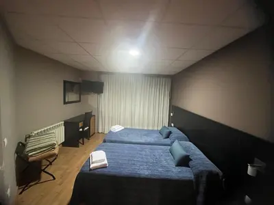 a bedroom with two blue beds and a television at Pension Luscofusco in Puebla de Trives