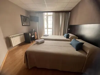 a hotel room with two beds and a window at Pension Luscofusco in Puebla de Trives