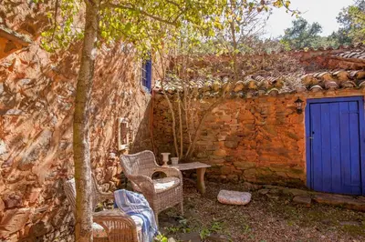 a stone wall with a blue door and chairs and a table at Arzipreste IV La Casita del Jardín in León