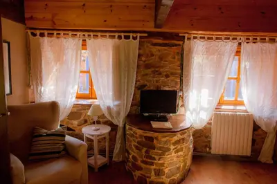 a living room with white curtains and a stone wall at Arzipreste IV La Casita del Jardín in León