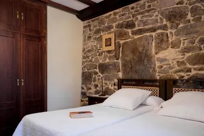 two beds in a room with a stone wall at Casa Roan y Casa Grande in Lodoso