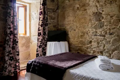 a bedroom with a bed in a stone wall at Casa Roan y Casa Grande in Lodoso