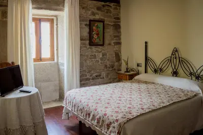 a bedroom with a bed and a table and a window at Casa Roan y Casa Grande in Lodoso