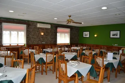 a dining room with tables and chairs and green walls at Hotel Restaurante Las Camelias in Jarrio