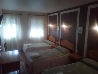 a room with three beds in a room at Hotel Restaurante Las Camelias in Jarrio
