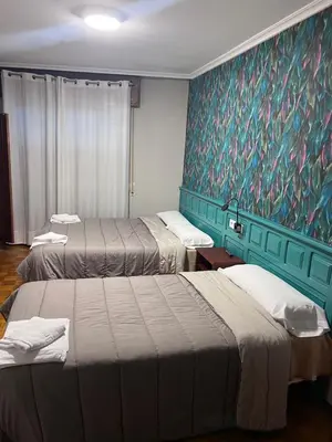 a room with three beds and a painting on the wall at Hotel Celta Galaico in Viveiro