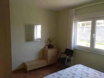 a bedroom with a bed and a dresser and a window at Urbanización Mar Cantábrico in Barreiros