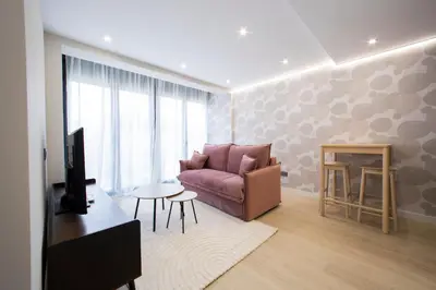 a living room with a pink couch and a table at Apartamentos O Devezo in Villalba