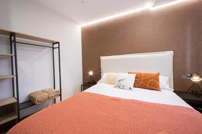 a bedroom with a large bed with orange sheets and pillows at Apartamentos O Devezo in Villalba