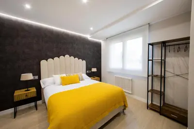 a bedroom with a large bed with a yellow blanket at Apartamentos O Devezo in Villalba