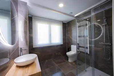 a bathroom with a toilet and a glass shower at Apartamentos O Devezo in Villalba