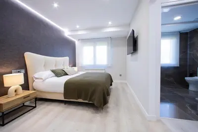a bedroom with a bed and a television and a bathroom at Apartamentos O Devezo in Villalba