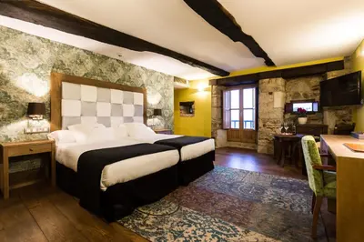 a bedroom with a large bed and a desk and a kitchen at Pazo da Pena Manzaneda in Manzaneda