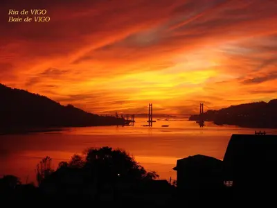 a sunset over the water with a bridge in the background at casa teno in Parada de Achas