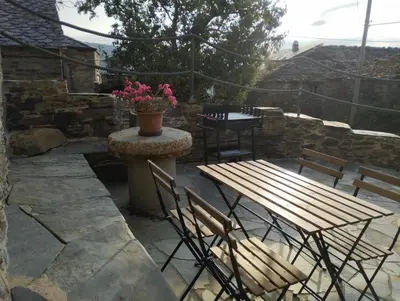 a wooden table and chairs on a stone patio at Casa Mameleiro e Casa Kintal in A Pontenova