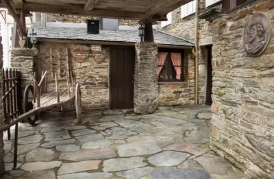 a stone house with a porch and a door at Casa Mameleiro e Casa Kintal in A Pontenova