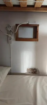 a room with a bed and a shelf on a wall at Albergue a Casina di Marcello in Palas de Rei