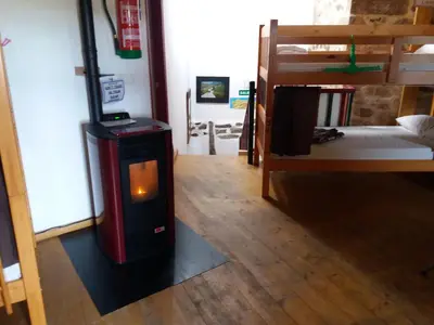 a wood stove in a room with a bunk bed at Albergue a Casina di Marcello in Palas de Rei