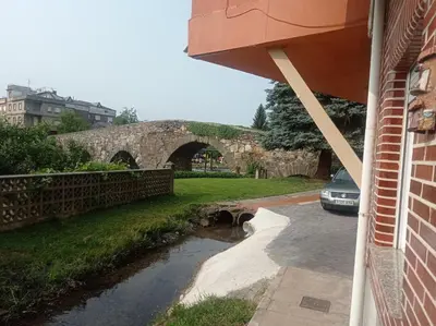 a car parked next to a building with a stone bridge at El Rincón del Cúa in Vega de Espinareda