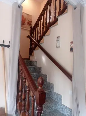 a staircase in a home with wooden railings and white walls at El Rincón del Cúa in Vega de Espinareda
