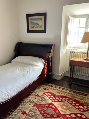 a bedroom with a bed and a table and a window at Casona Puerto de Vega in Puerto de Vega