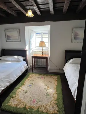 a bedroom with two beds and a table and a window at Casona Puerto de Vega in Puerto de Vega