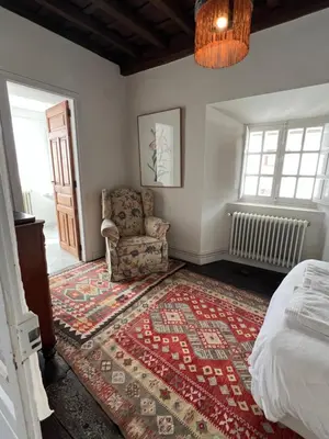 a bedroom with a bed and a chair and a rug at Casona Puerto de Vega in Puerto de Vega