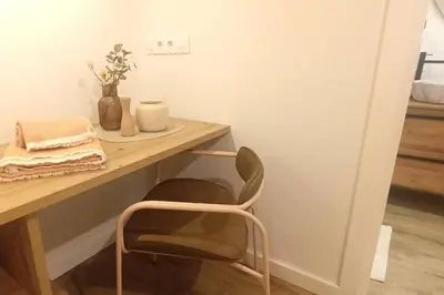 a chair sitting next to a wooden table with a desk at Sienna Home Apartamento in Santiago de Compostela
