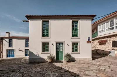 a white house with a green door on a stone driveway at Casa Juanita in Melide