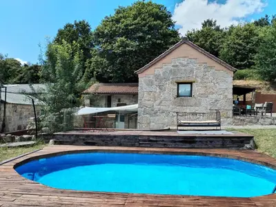 a swimming pool in front of a stone house at A Casa do outeiro in Ponteareas
