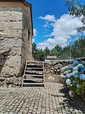 a stone building with a ladder next to a wall at A Casa do outeiro in Ponteareas