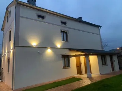 a white house with lights on the side of it at Apartamentos Casa Benito in San Tirso de Abres