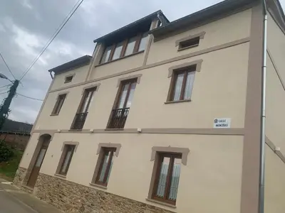 a large white building with windows on a street at Apartamentos Casa Benito in San Tirso de Abres