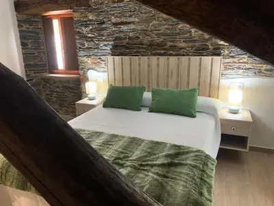 a bedroom with a large bed with two green pillows at Apartamentos Casa Benito in San Tirso de Abres