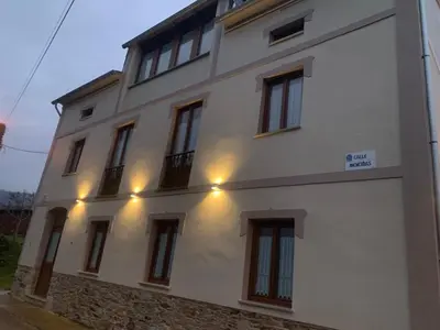 a white building with windows and lights on it at Apartamentos Casa Benito in San Tirso de Abres