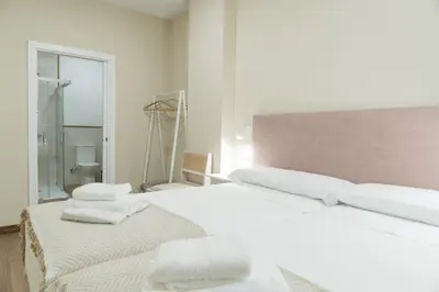 a bedroom with a large white bed with towels on it at Pensión María Castaña in Puebla del Brollón