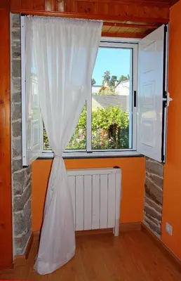 a window with a white curtain in a room at Aqua Rooms Sarria in Sarria