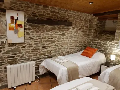 a bedroom with two beds and a stone wall at Aqua Rooms Sarria in Sarria