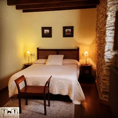 a bedroom with a bed with two lamps and a chair at Hotel Rural Casona Trabadelo in Vegadeo