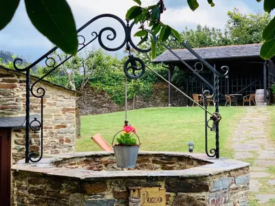 a stone fountain with a plant in a bucket at Hotel Rural Casona Trabadelo in Vegadeo